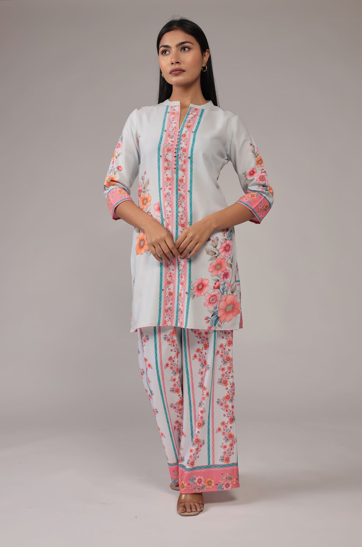 Model wearing a beautiful light grey digital print co-ord set from The Navra, featuring vibrant pink and blue floral patterns on a collared kurta and comfortable wide-leg pants. Ideal for casual or everyday elegance.