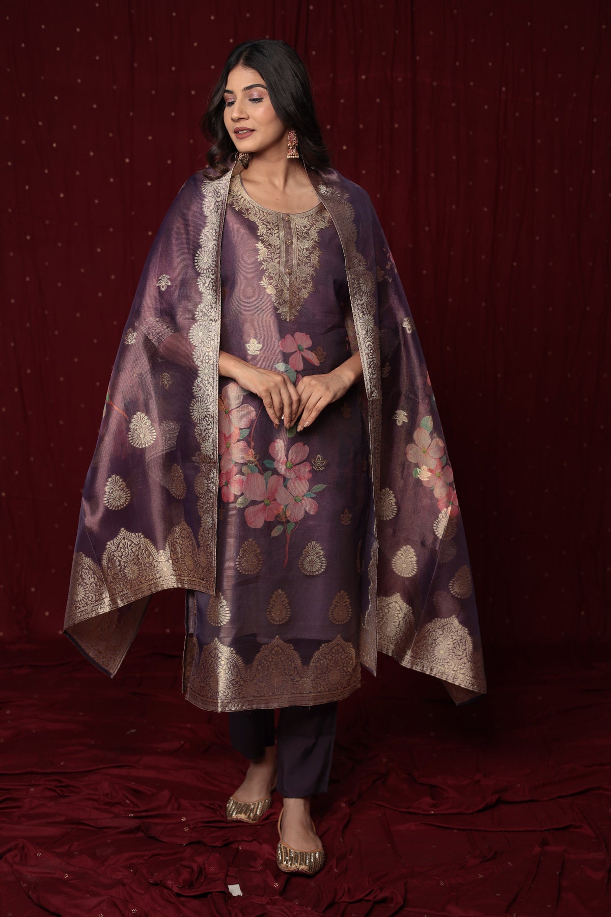 Model wearing deluxe jacquard organza purple suit from The Navra, featuring rich floral prints, intricate embroidery, and a grand jacquard dupatta, with soft silk pants. Perfect for luxurious festive occasions.