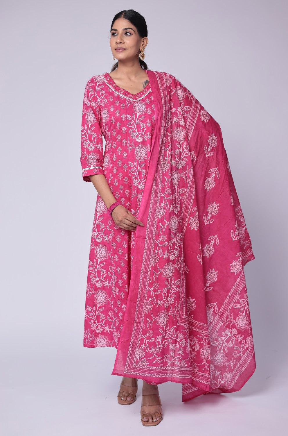 Model wearing a vibrant fuchsia pink cotton Anarkali dupatta set from The Navra, featuring intricate handwork on the neck, a flowing Jaipuri printed kurta, and a matching printed dupatta. Ideal for comfortable daily or festive ethnic wear.