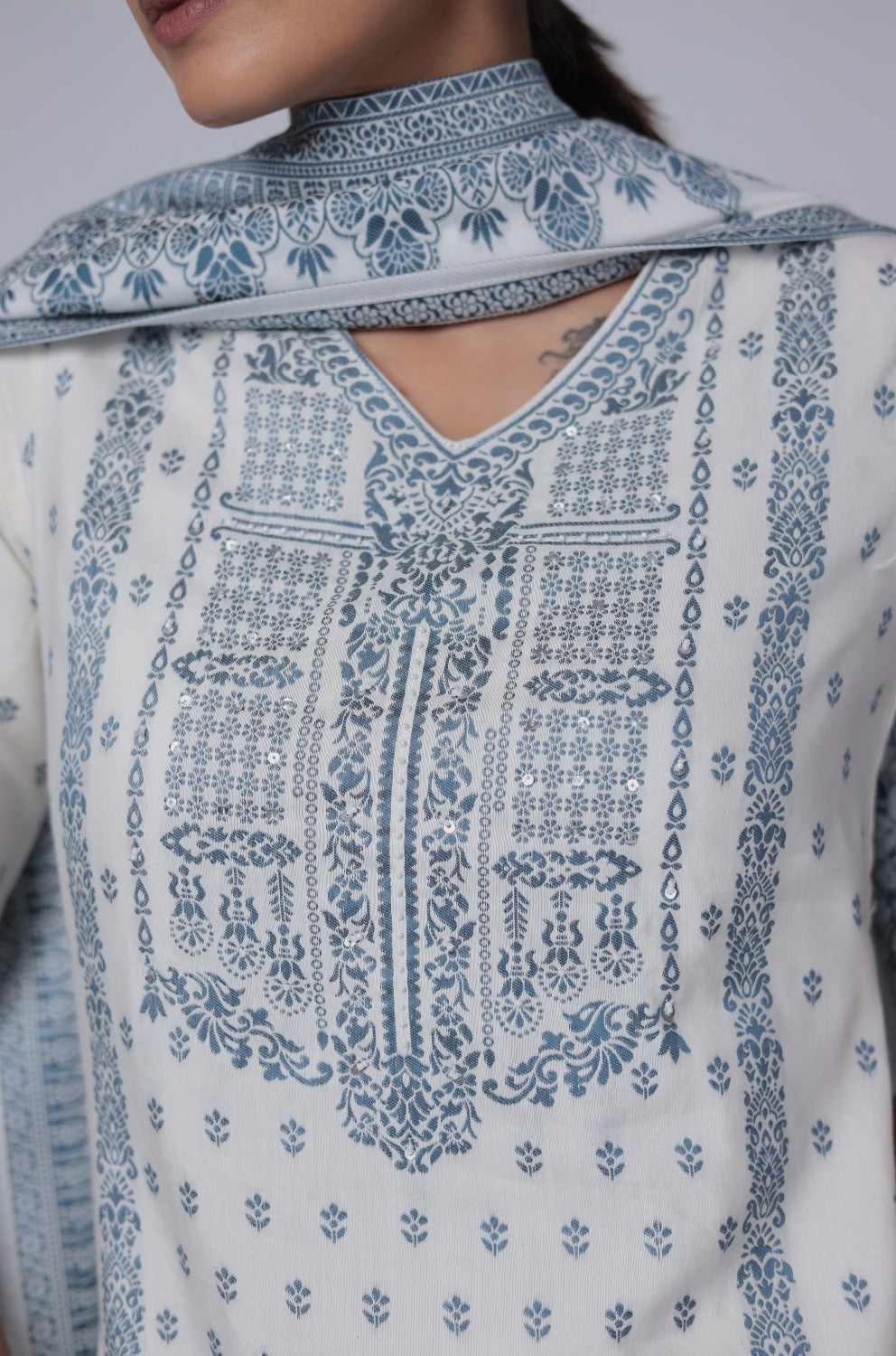 Close-up of the exquisite blue detailing and embroidery on the V-neckline and front of the off-white cotton jacquard kurta, highlighting intricate craftsmanship.