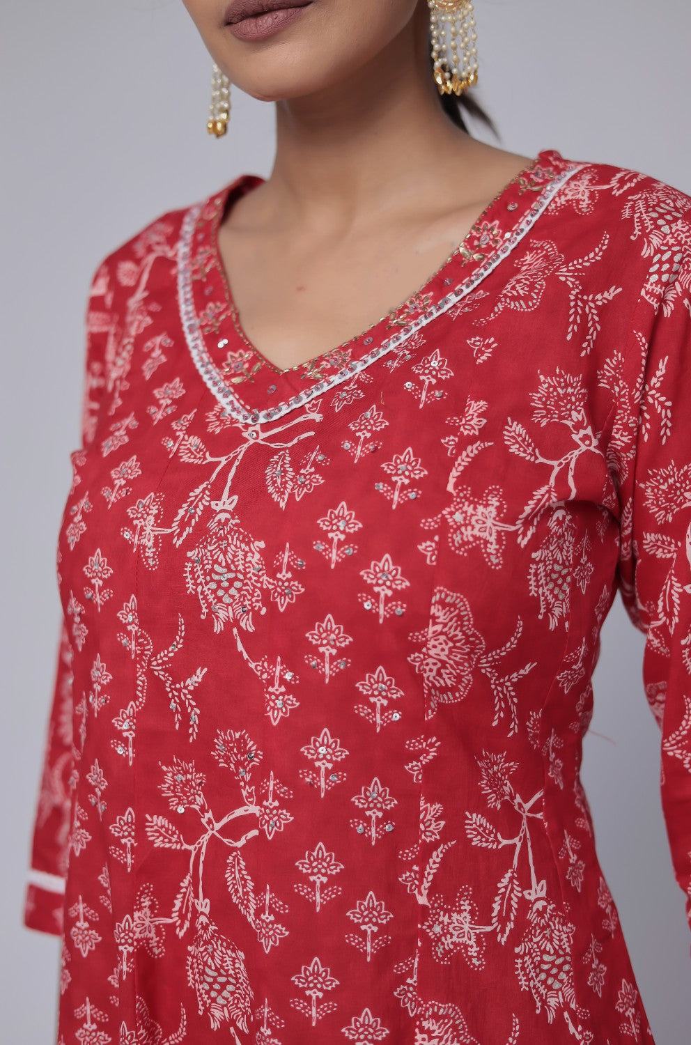 Close-up of the delicate white handwork embroidery on the V-neckline of the red cotton Anarkali kurta, highlighting intricate details.