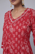 Close-up of the delicate white handwork embroidery on the V-neckline of the red cotton Anarkali kurta, highlighting intricate details.