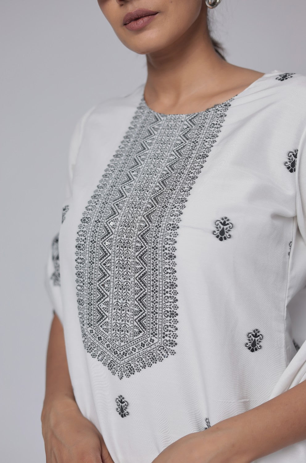 Close-up of the exquisite black geometric detailing and embroidery on the round neckline and front of the off-white cotton jacquard kurta, highlighting intricate craftsmanship.