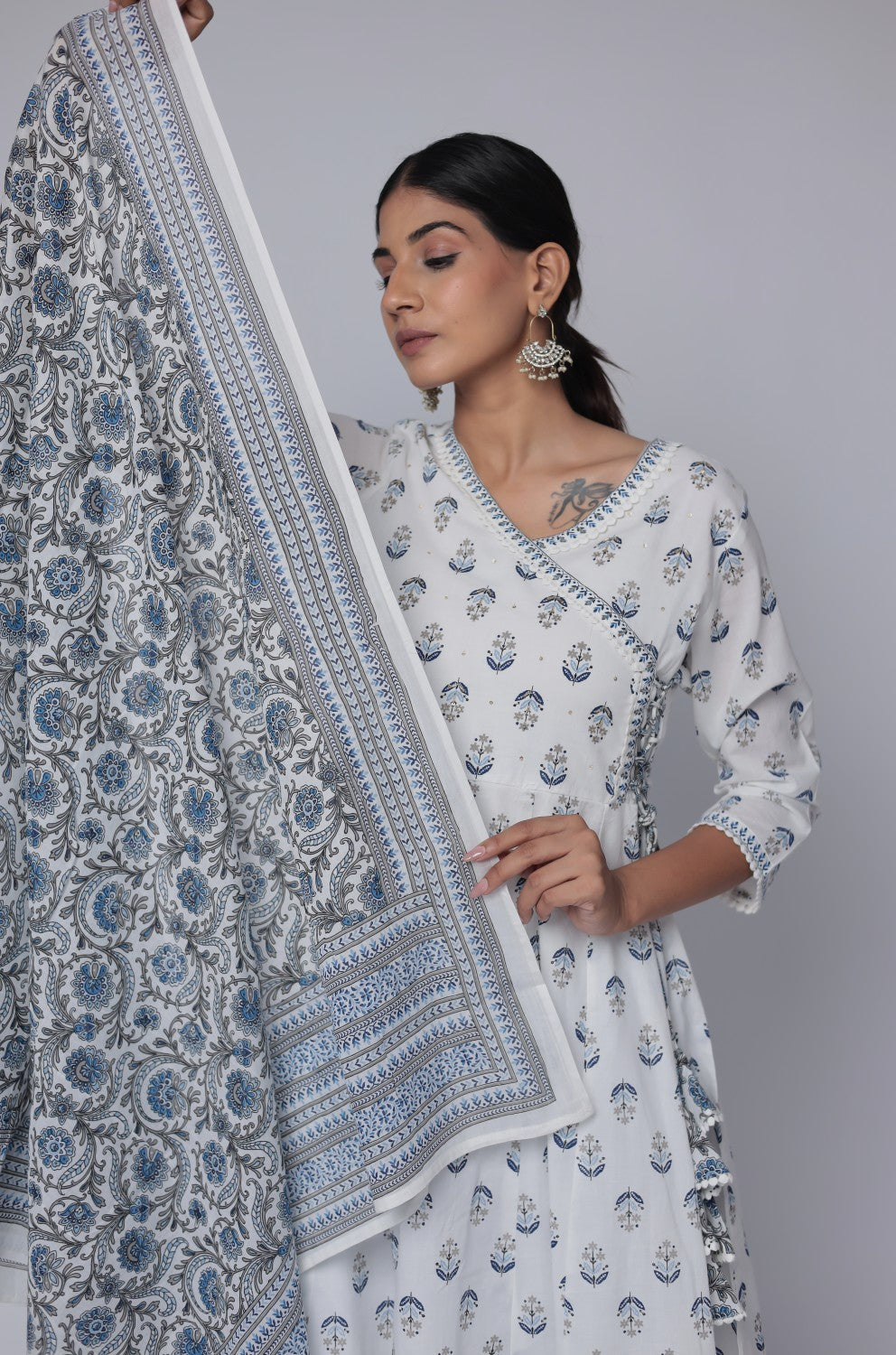 Flat lay arrangement of the complete white and blue cotton Anarkali set, featuring a Jaipuri print kurta with handwork and crochet lace hem, printed dupatta, and matching pants, showcasing full design details.
