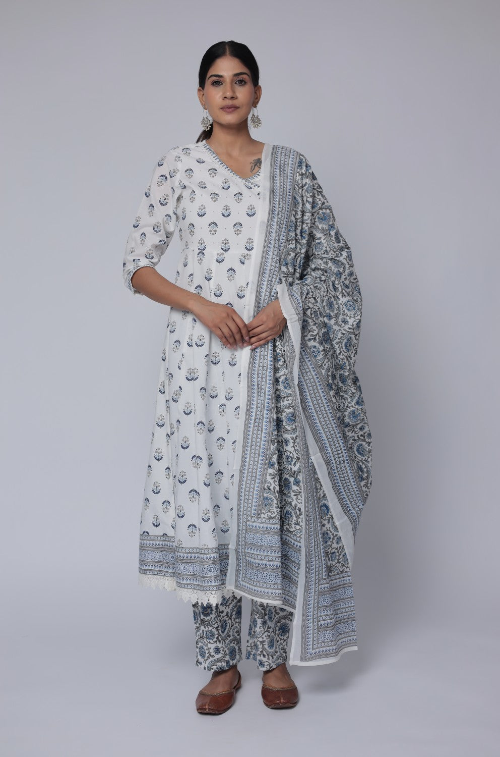 Woman wearing a white and gray patterned traditional outfit on a plain background