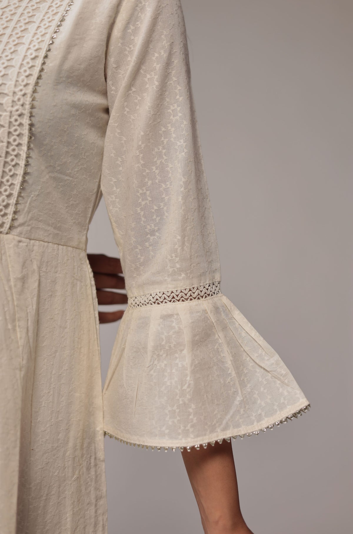 Detailed view of the flared bell sleeve and the premium white crochet fabric insert on the skirt of the cotton dobby dress.