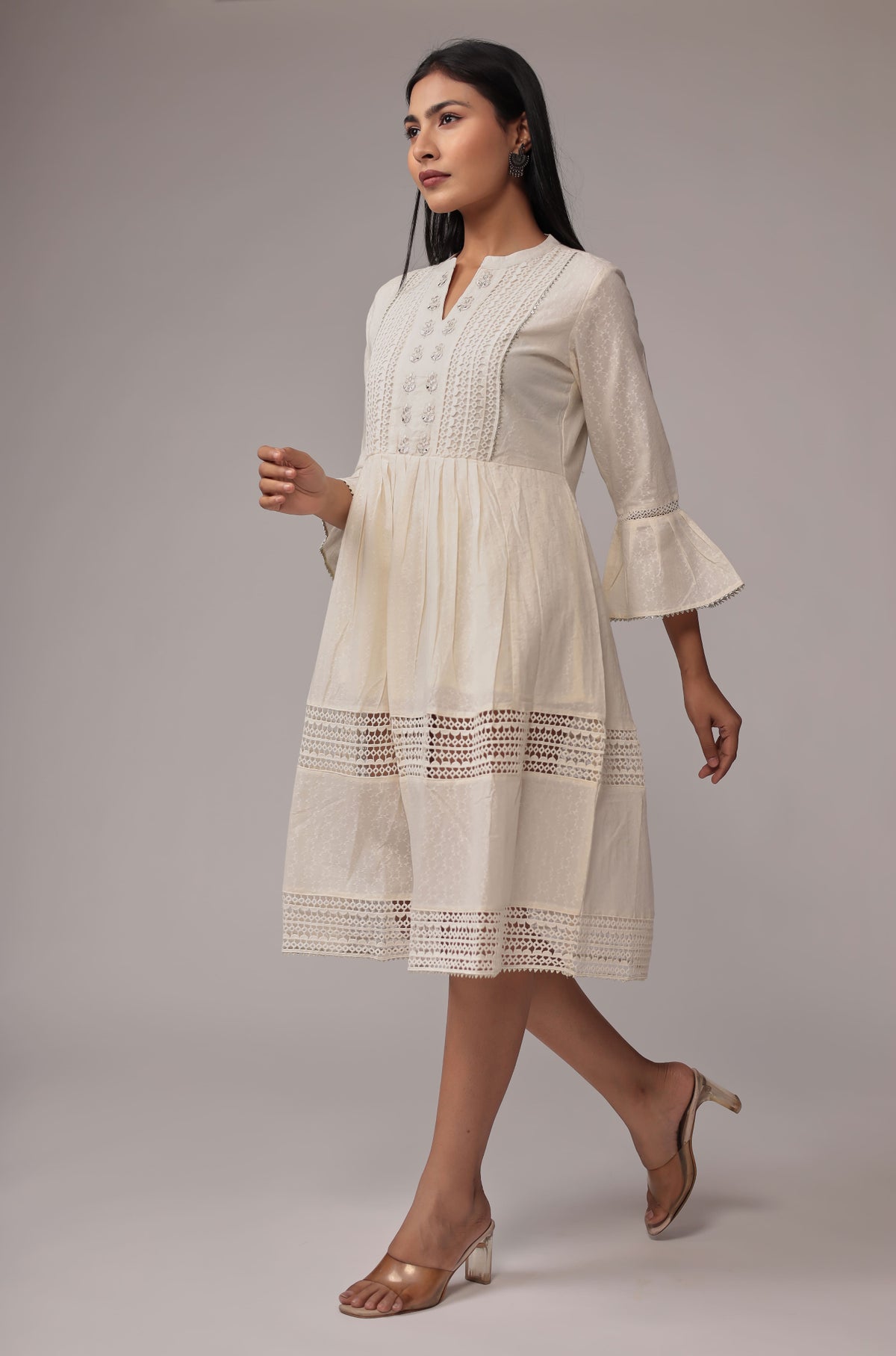 Model in a dynamic pose, showcasing the lightweight fabric and comfortable movement of the white cotton dobby dress with crochet details.