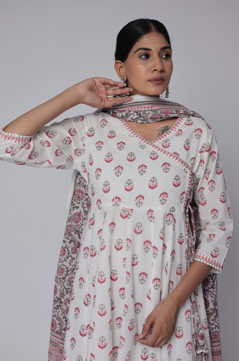Close-up of the delicate handwork on the V-neckline of the white and red cotton Anarkali kurta, with a glimpse of the Jaipuri print dupatta.