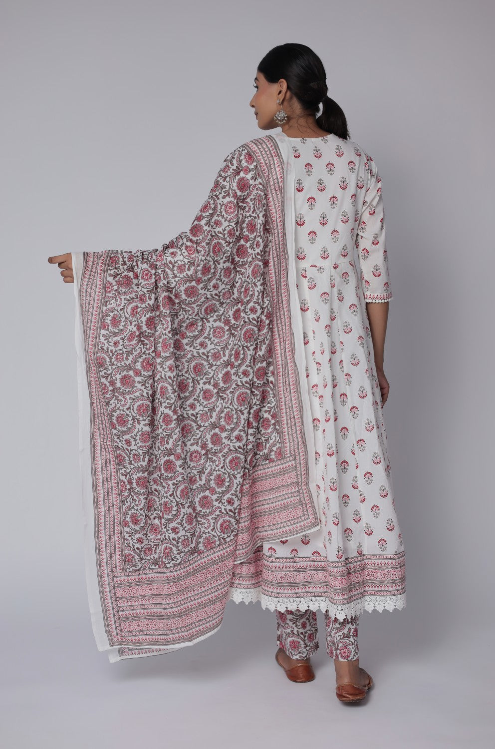 Woman wearing a traditional outfit with a floral pattern on a plain background