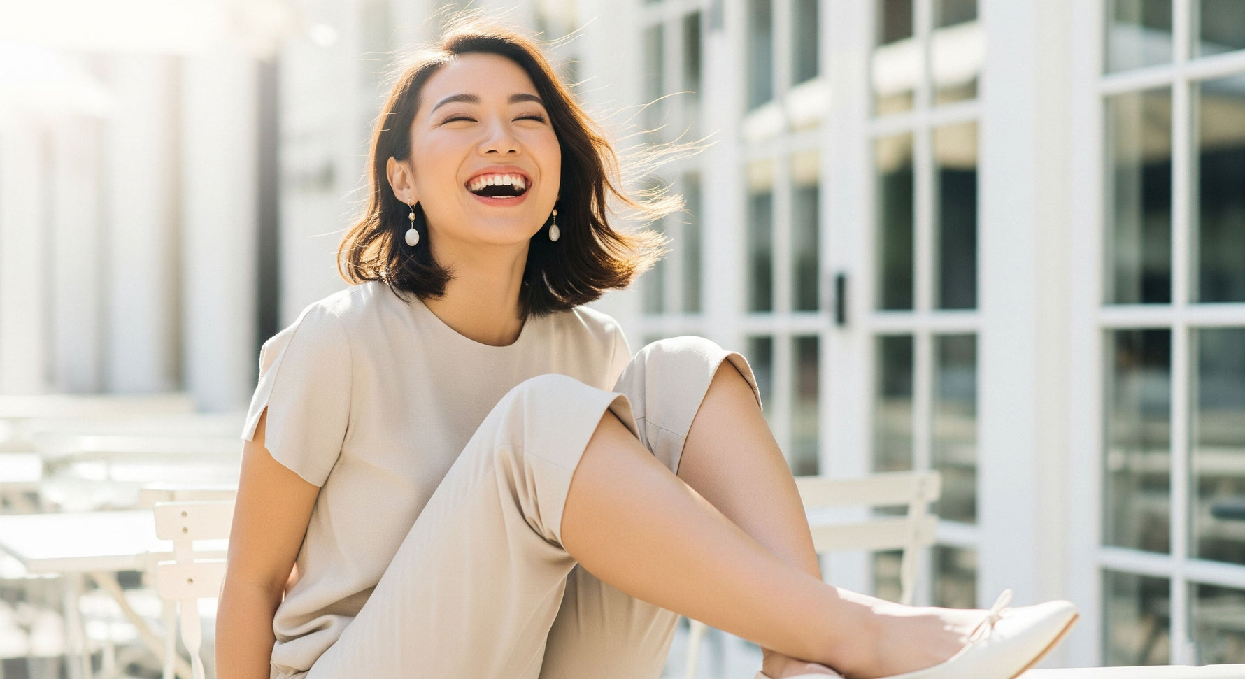 Happy woman laughing in a casual chic Capri pants outfit with a clean, bright background