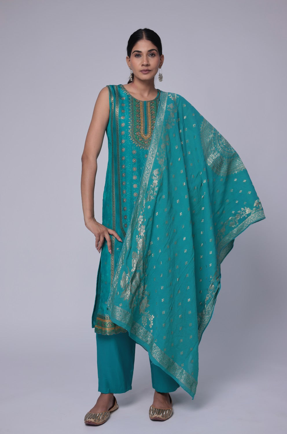 Model wearing a luxurious Banarasi Jacquard Chanderi Rama Green suit set from The Navra, featuring intricate gold woven patterns, a rich jacquard dupatta, and soft silk pants with inner lining. Ideal for grand festive or wedding occasions.