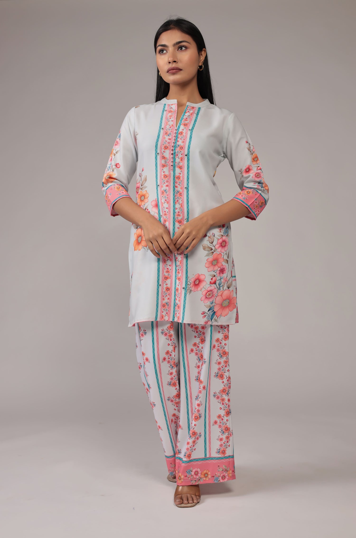 Model wearing a beautiful light grey digital print co-ord set from The Navra, featuring vibrant pink and blue floral patterns on a collared kurta and comfortable wide-leg pants. Ideal for casual or everyday elegance.

