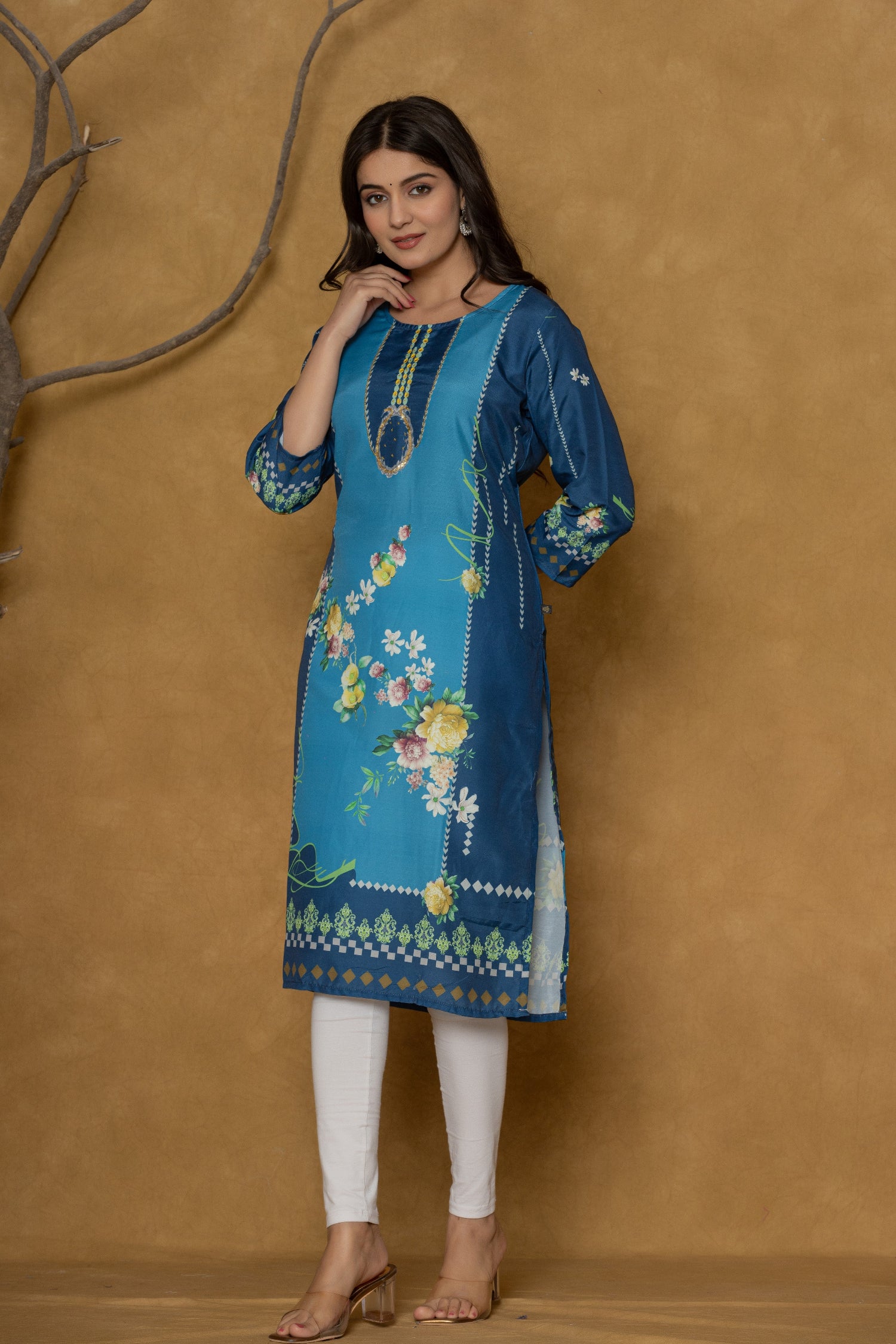 Model wearing a vibrant blue kurta from The Navra, intricately detailed with handwork on the round neck, featuring colorful floral prints, paired with white leggings. Ideal for comfortable daily or casual ethnic wear.