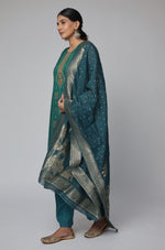 Side profile of model showcasing the comfortable fit and elegant drape of the bottle green Banarasi Jacquard Chanderi suit set with its woven jacquard dupatta.