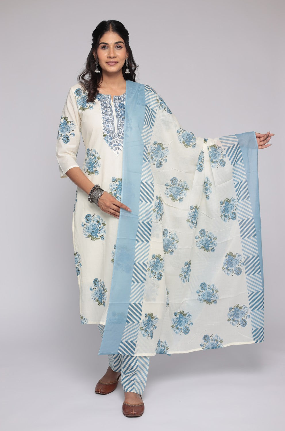 Model wearing a beautiful cream and blue Jaipuri print dupatta set from The Navra, with mulmul lining, featuring intricate embroidery on the neck, a floral printed kurta, striped dupatta, and matching pants. Ideal for comfortable daily or casual ethnic wear.