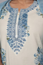 lose-up of the delicate neck embroidery and vibrant blue floral Jaipuri print on the cream kurta, highlighting intricate details.
