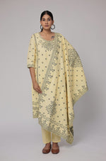 Model wearing an elegant cream yellow cotton jacquard dupatta set from The Navra, featuring intricate dark grey merging embroidery on the front of the kurta and a matching patterned dupatta. Ideal for comfortable daily or semi-formal ethnic wear.