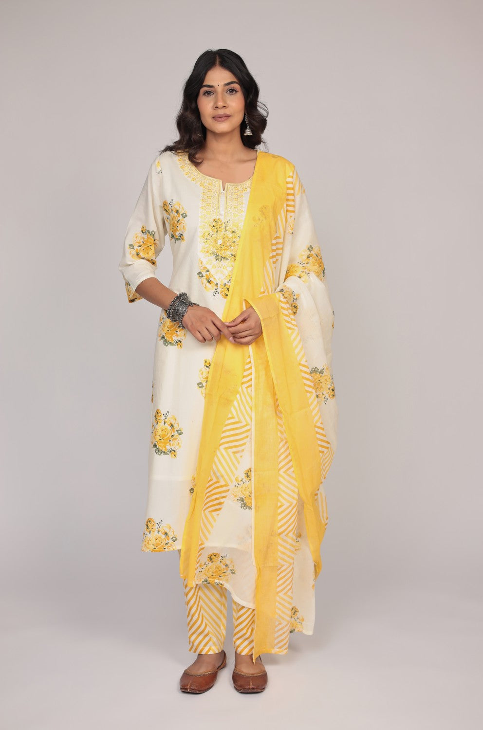 Model wearing a vibrant cream and yellow Jaipuri print kurta set from The Navra, featuring neck embroidery, mulmul lining, a printed kurta, striped pants, and a matching dupatta. Ideal for comfortable daily or festive ethnic wear.
