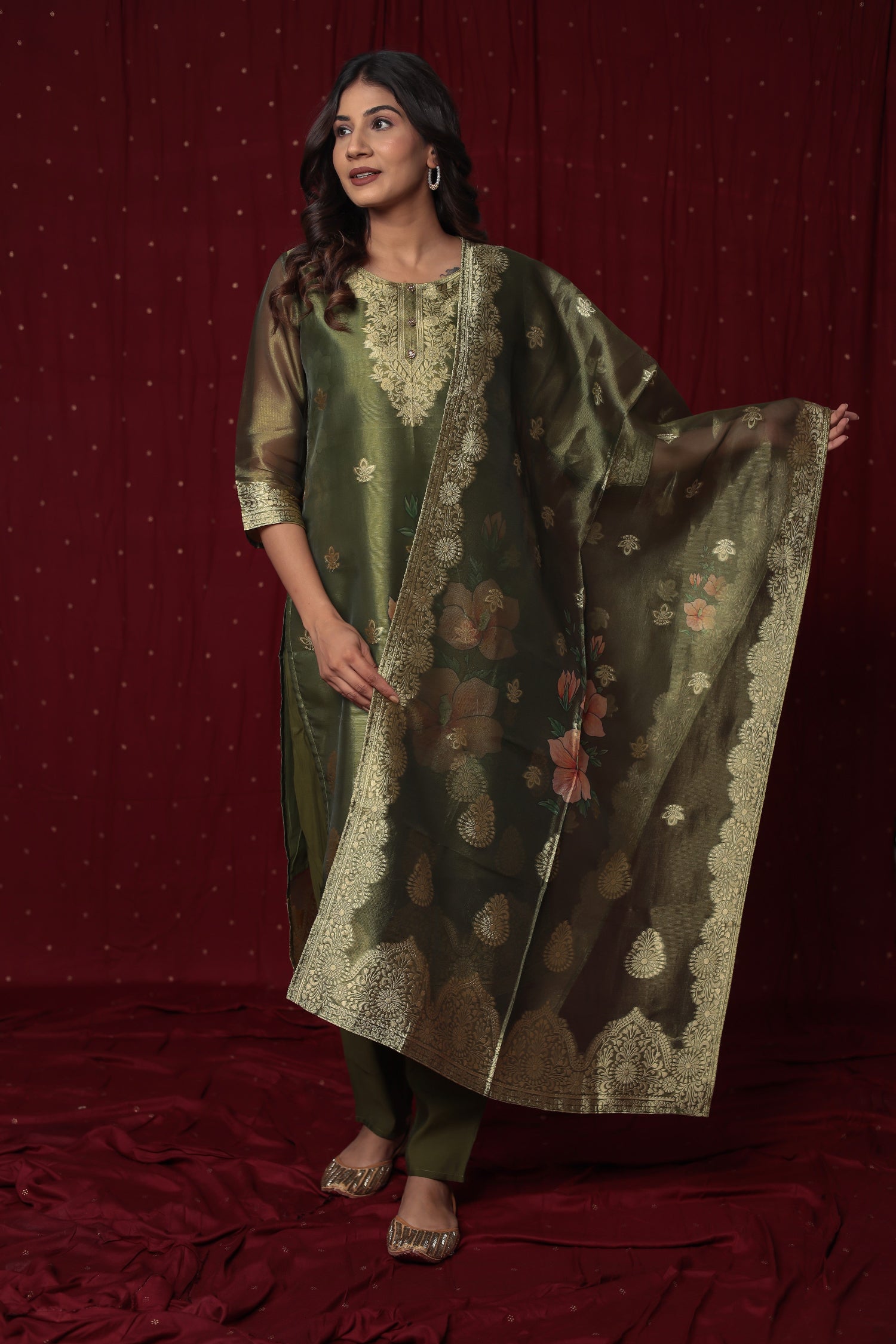 Model wearing deluxe jacquard organza olive green suit from The Navra, featuring intricate gold embroidery and woven patterns, with a matching jacquard dupatta and soft silk pants. Ideal for festive and semi-formal occasions.