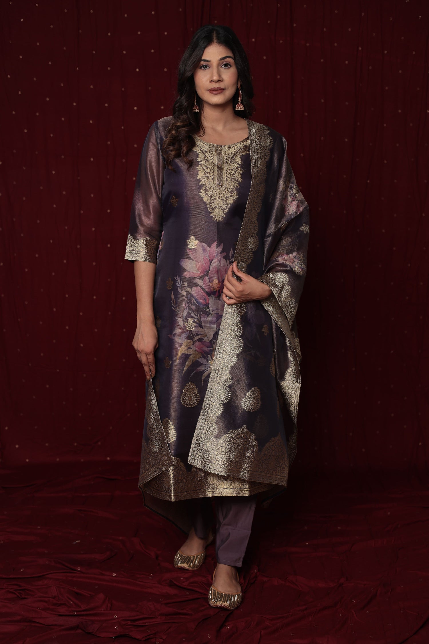 Model wearing a luxurious Deluxe Jacquard Organza purple suit from The Navra, featuring rich woven patterns on the kurta, a floral jacquard dupatta, and soft silk pants with inner lining. Ideal for grand festive or formal occasions.