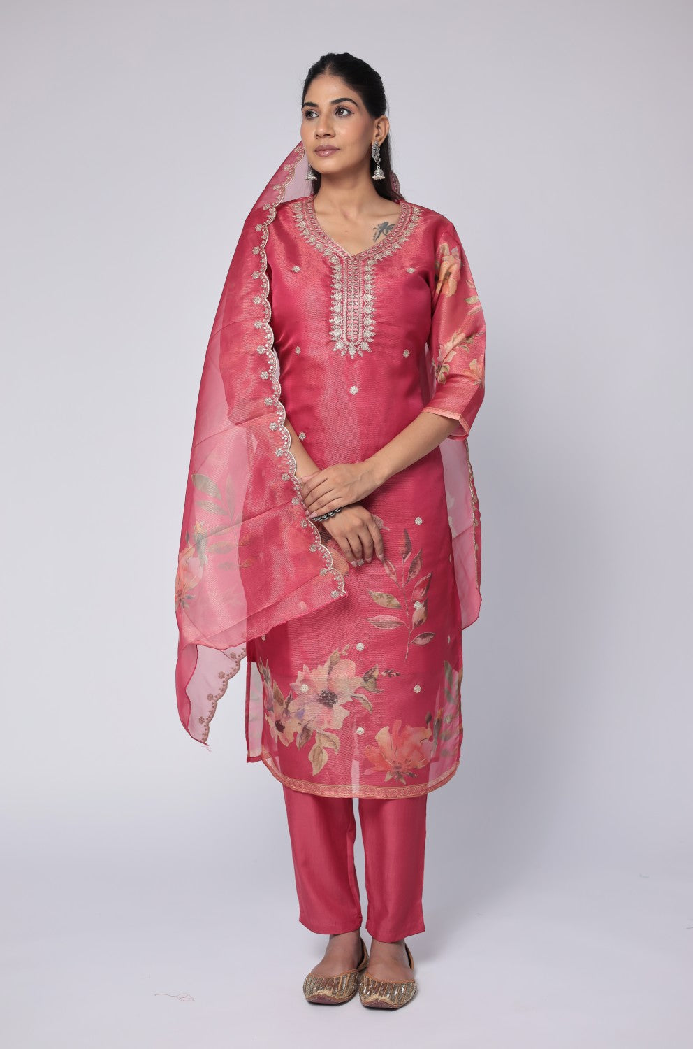 Model wearing a deluxe shimmer organza deep pink suit from The Navra, featuring intricate embroidery on the kurti, an elegant floral embroidered dupatta, and soft muslin pants. Ideal for festive and special occasions.