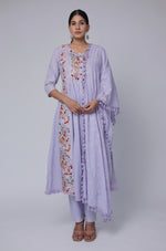 Model wearing a beautiful lavender embroidered Anarkali kurta set from The Navra, featuring multi-color floral handwork on a cotton dobby base, a flowing Anarkali kurta, and a matching dupatta. Ideal for comfortable daily or festive ethnic wear.