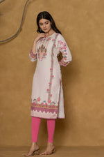 Model wearing a light pink kurta from The Navra, featuring intricate handwork on the round neck and colorful floral-geometric prints on the hem and sleeves, paired with bright pink leggings. Ideal for comfortable daily or casual ethnic wear.