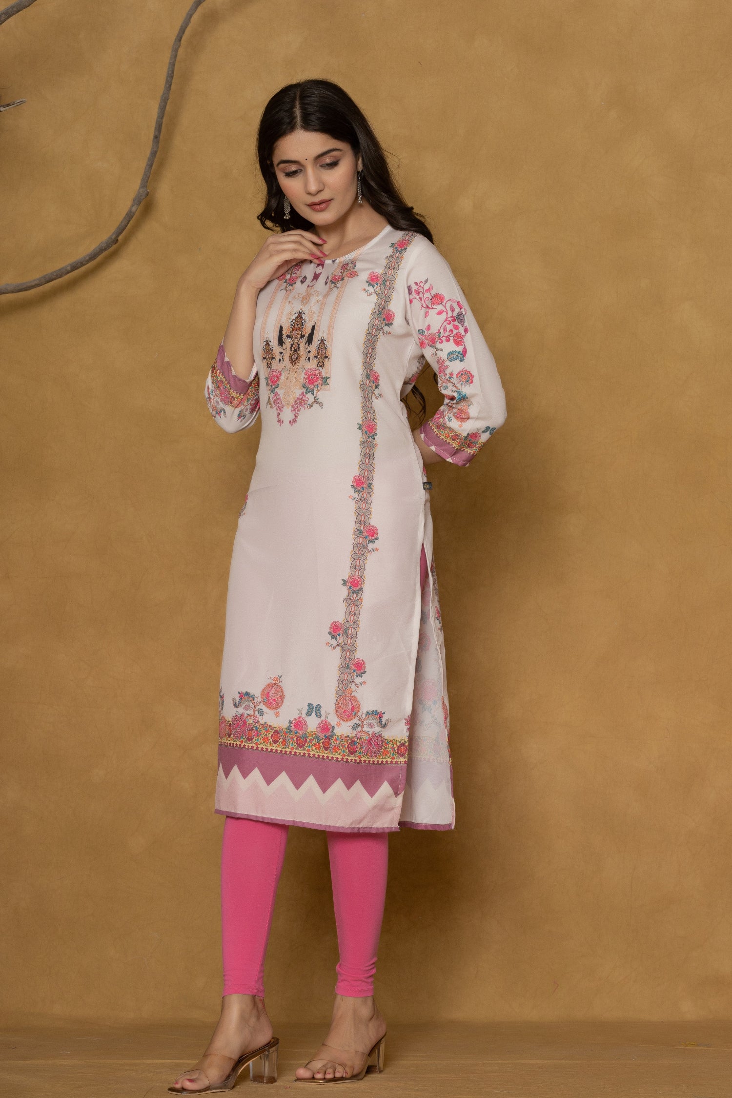 Model wearing a light pink kurta from The Navra, featuring intricate handwork on the round neck and colorful floral-geometric prints on the hem and sleeves, paired with bright pink leggings. Ideal for comfortable daily or casual ethnic wear.