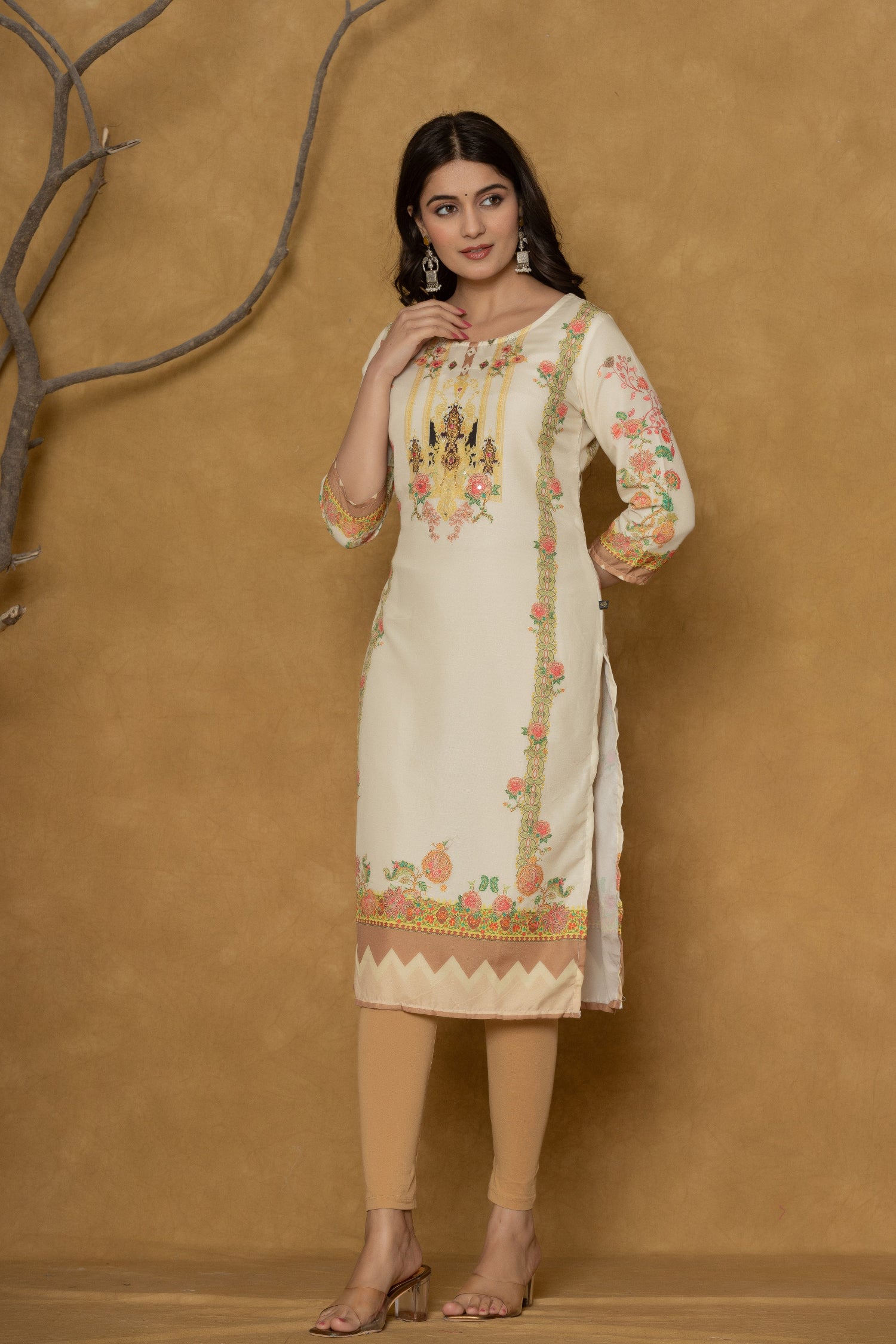 Model wearing a light yellow kurta from The Navra, featuring intricate handwork on the round neck and colorful floral prints on the hem and sleeves, paired with light beige leggings. Ideal for comfortable daily or casual ethnic wear.