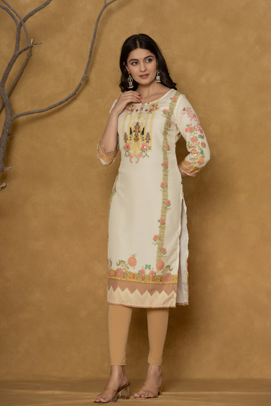 Model wearing a light yellow kurta from The Navra, featuring intricate handwork on the round neck and colorful floral prints on the hem and sleeves, paired with light beige leggings. Ideal for comfortable daily or casual ethnic wear.