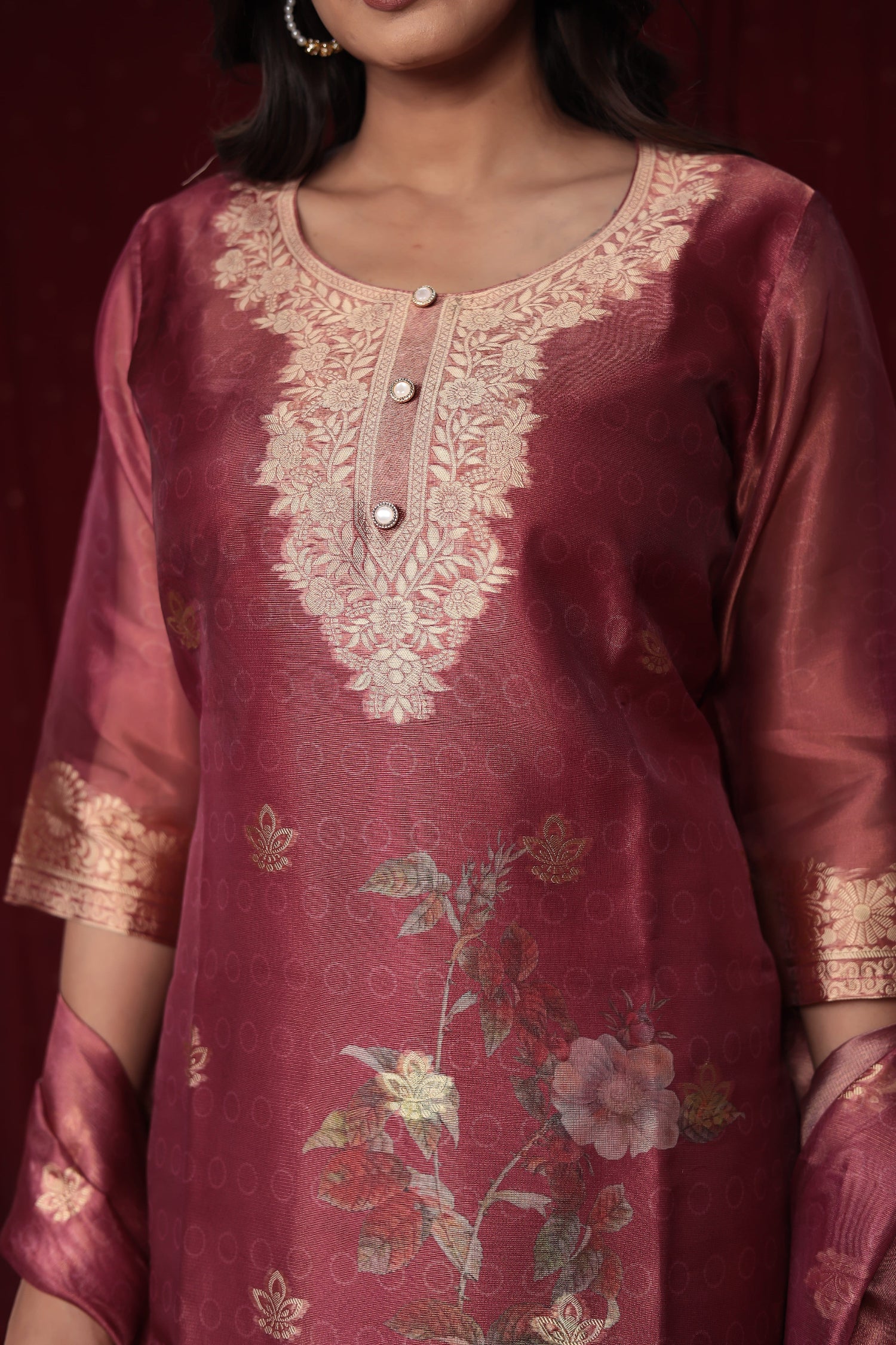 Close-up of the exquisite gold embroidery on the neckline and subtle woven jacquard patterns on the rich maroon organza kurti.