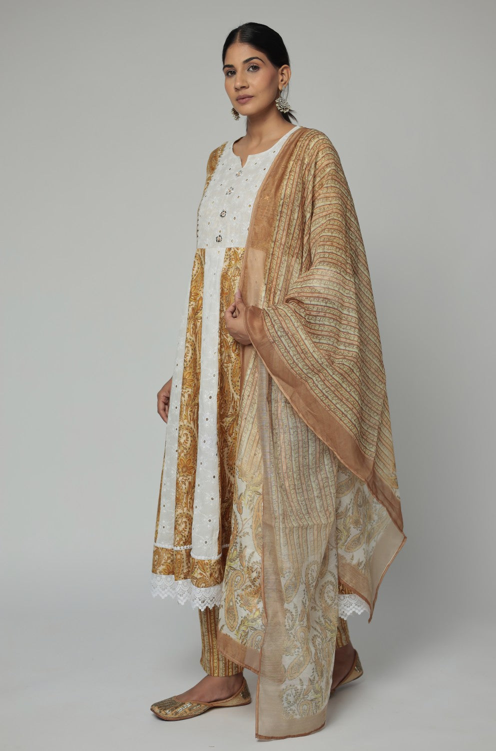 Detailed view of the intricate border design and white lace on the hemline of the mustard yellow Schiffli Anarkali kurta.