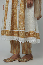 Traditional outfit with white and gold embroidery on a plain background