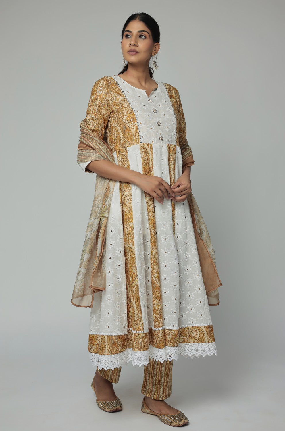 Model in a relaxed stance, highlighting the full length and comfortable design of the mustard yellow Schiffli Anarkali set with mirror work.