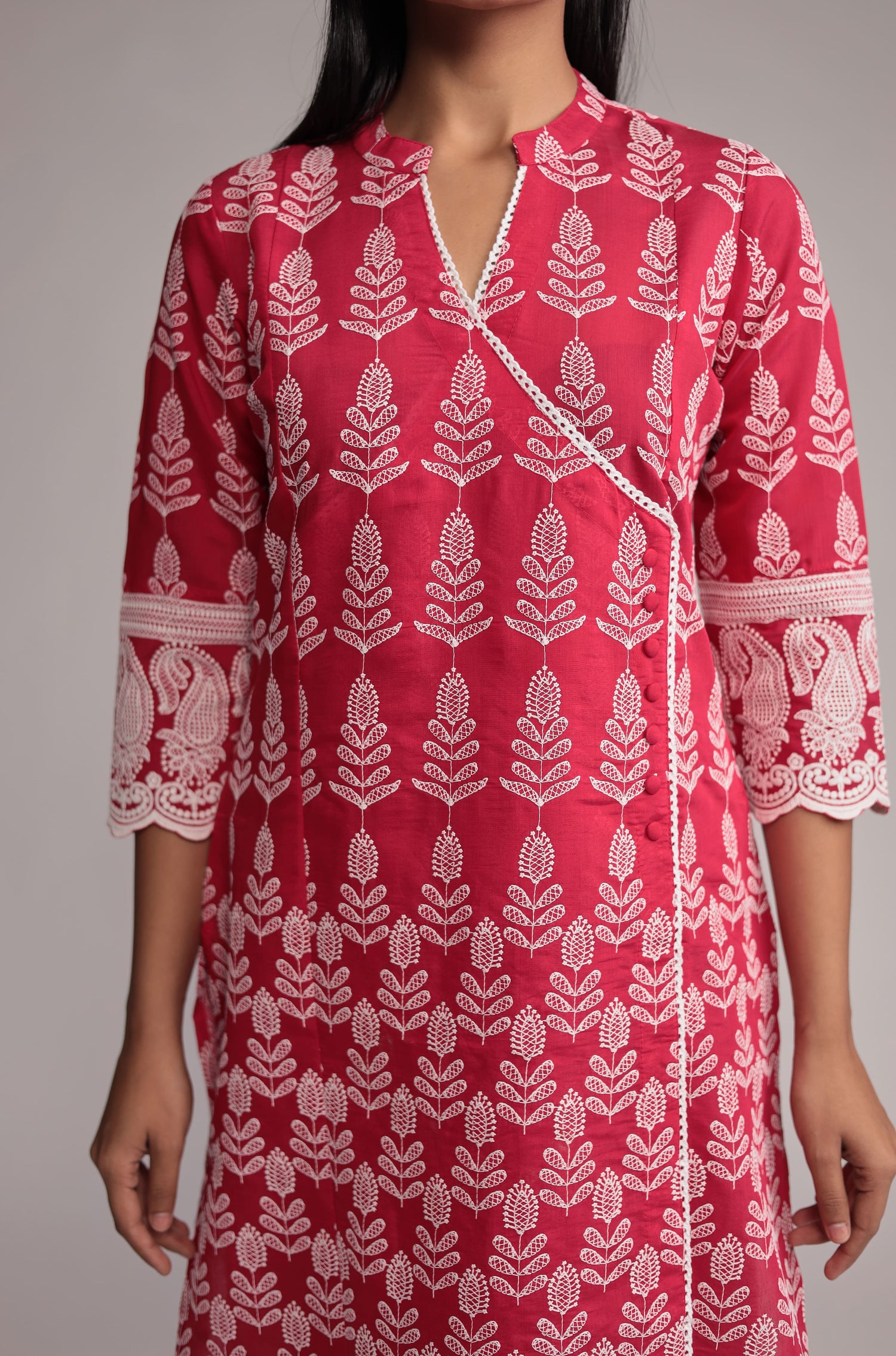 Close-up of the exquisite allover embroidery and intricate patterns on the neckline and front of the pink kurta.