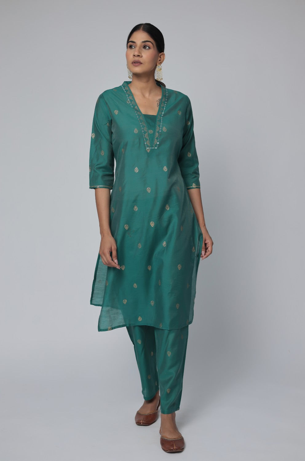 Model wearing an elegant Rama Green Chanderi Silk co-ord set from The Navra, featuring intricate mirror embroidery and subtle gold motifs on the kurta, paired with comfortable matching pants. Ideal for festive or sophisticated daily wear.