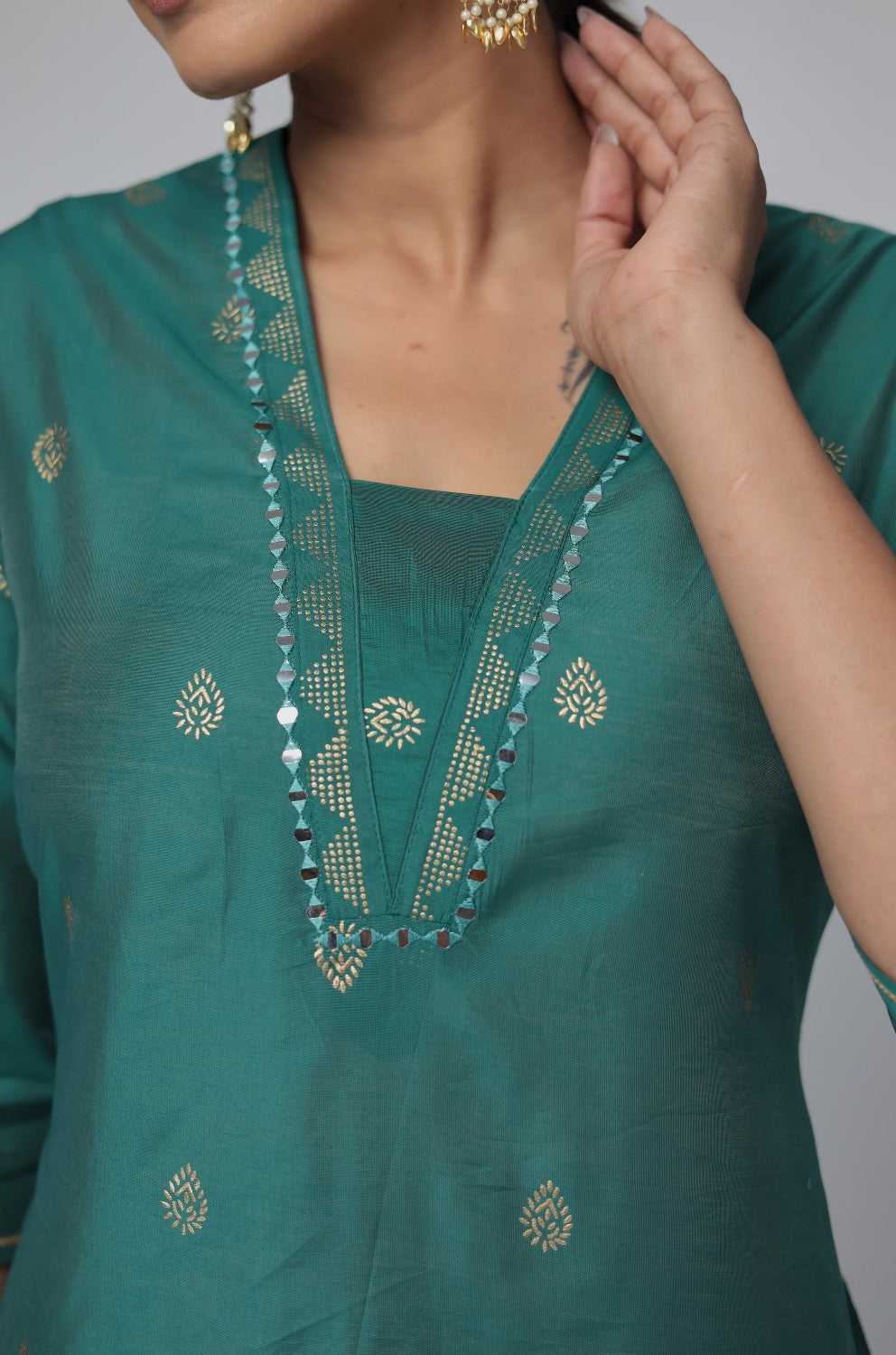 Close-up of the exquisite mirror embroidery and subtle gold motifs on the round neckline of the Rama Green Chanderi Silk kurta, highlighting intricate craftsmanship.