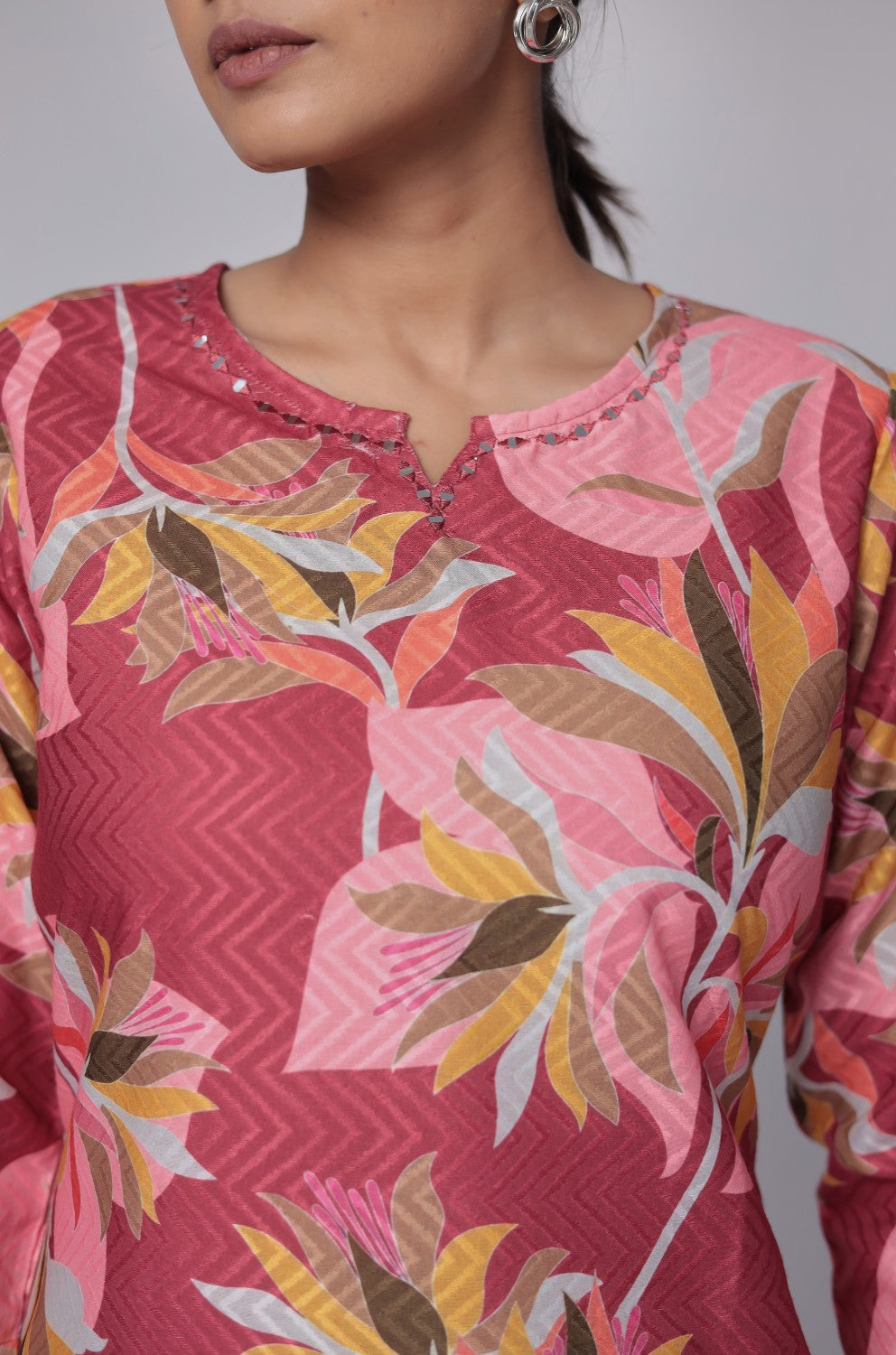 Close-up of the vibrant red, pink, and yellow floral print and distinctive dobby texture on the red and pink premium cotton kurti.