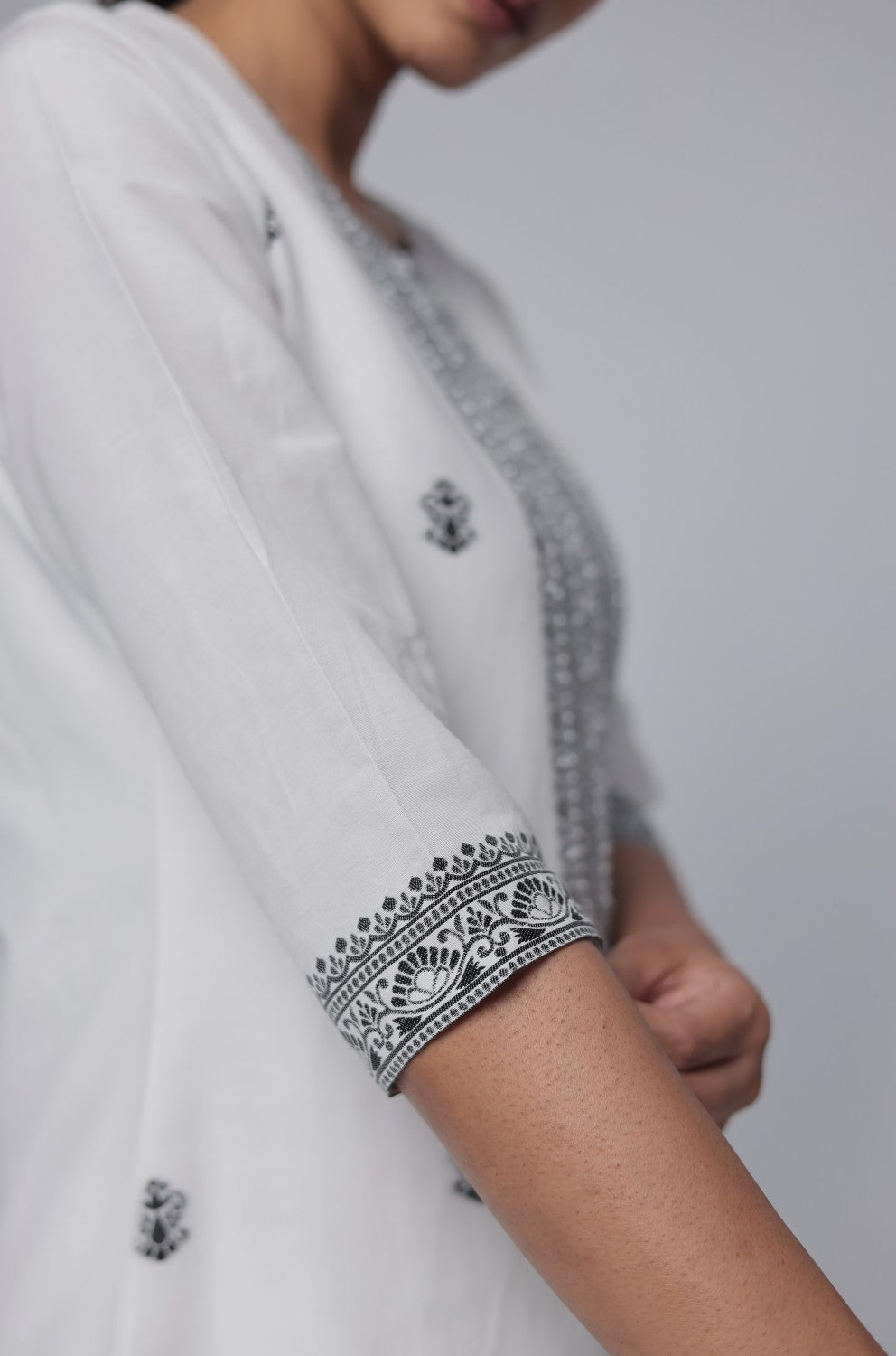 Detailed view of the patterned sleeve and hemline detailing on the off-white and black cotton jacquard kurta.