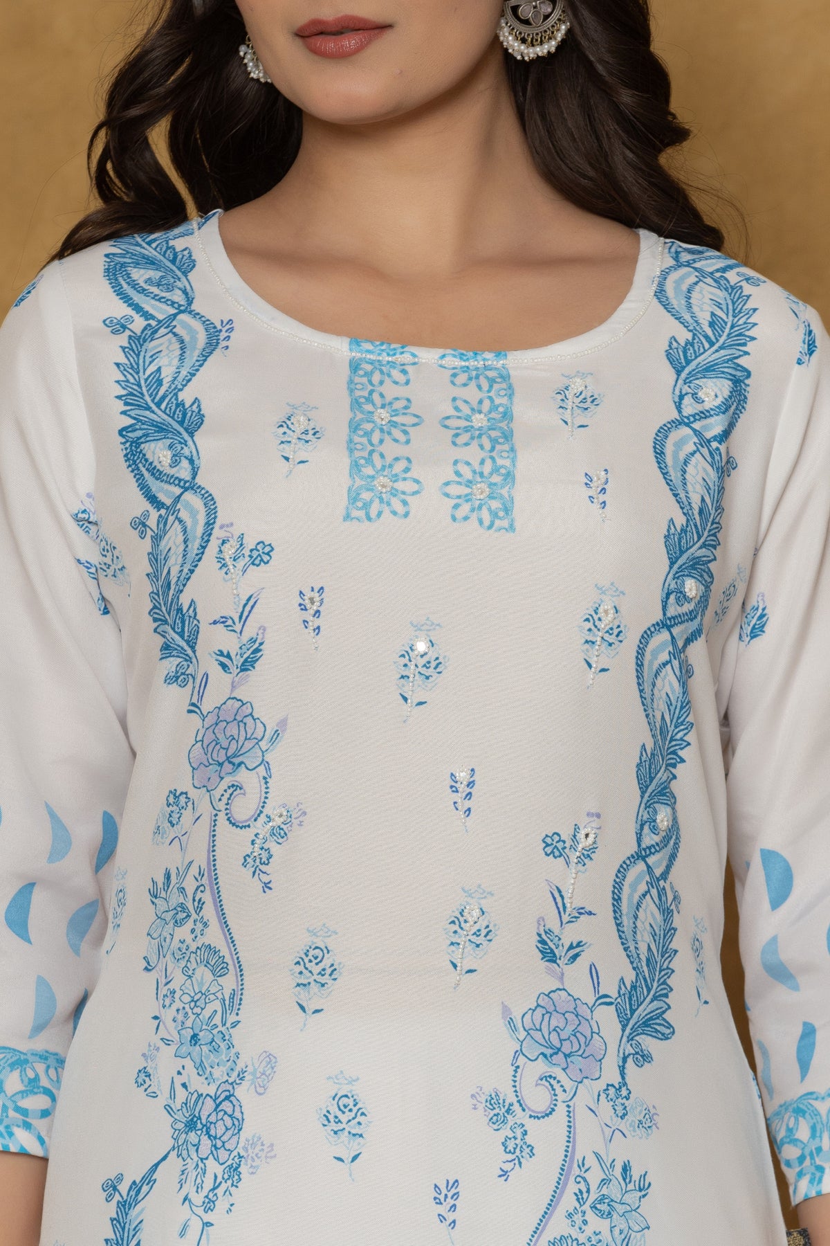 Close-up of the delicate blue handwork embroidery and detailing on the round neckline of the white kurta, highlighting fine craftsmanship.
