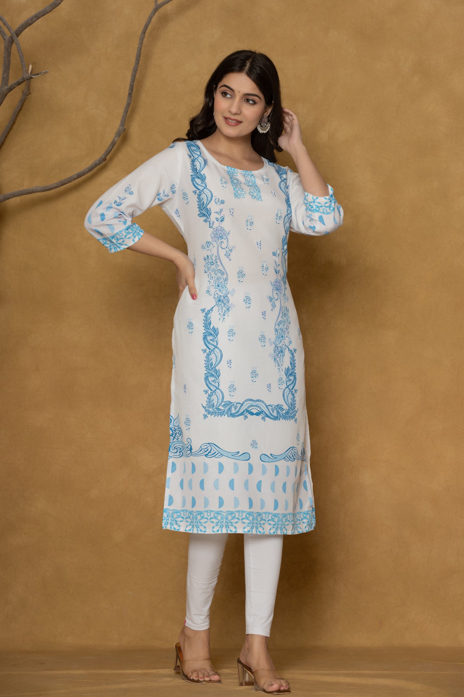 Model wearing a white kurta from The Navra, intricately detailed with blue handwork on the round neck and complementing block prints, paired with white leggings. Ideal for comfortable daily or casual ethnic wear.