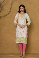 Close-up of the delicate floral and geometric pattern in lime green and orange along the hemline of the white pannel kurta, showcasing the fabric and design detail.