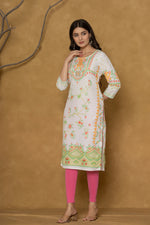 Model wearing a white and lime pannel kurta from The Navra, featuring intricate handwork on the round neck and delicate floral patterns in orange and green, paired with bright pink leggings. Ideal for casual and daily ethnic wear.