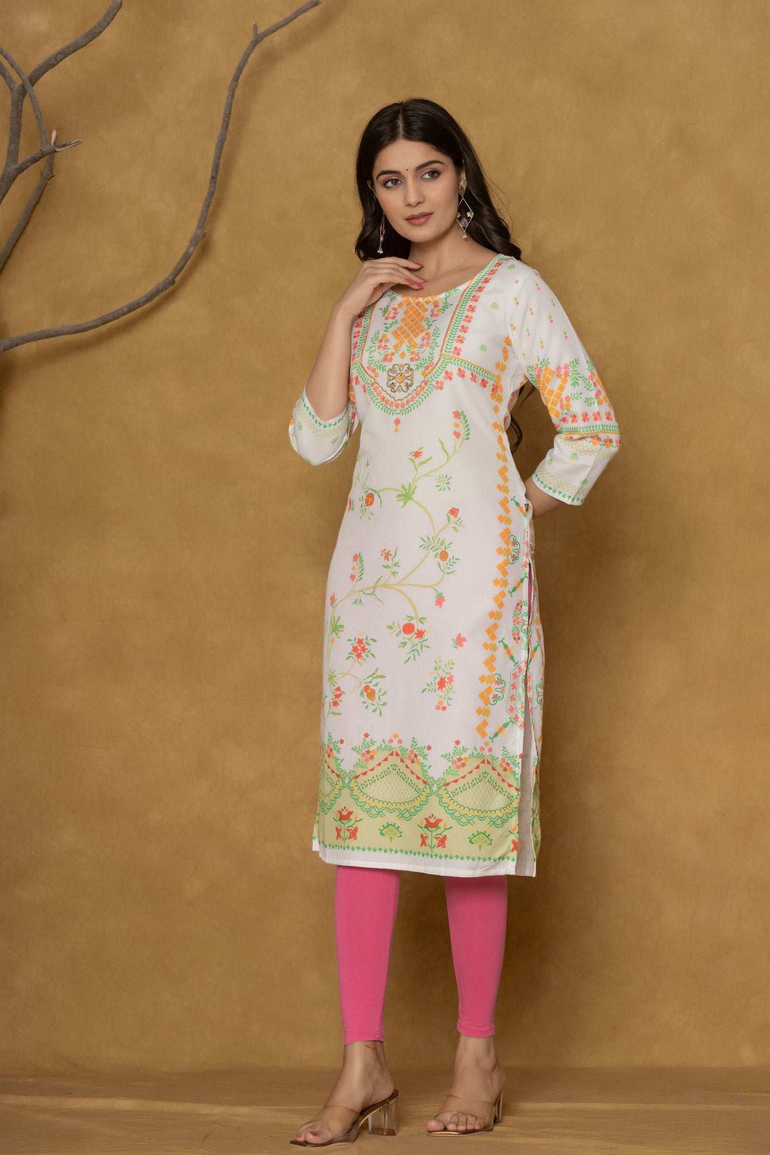 Model wearing a white and lime pannel kurta from The Navra, featuring intricate handwork on the round neck and delicate floral patterns in orange and green, paired with bright pink leggings. Ideal for casual and daily ethnic wear.
