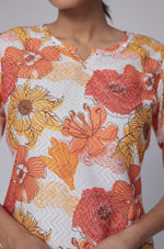 Close-up of the vibrant orange and yellow floral print and distinctive dobby texture on the white premium cotton kurti.