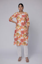 Model wearing a vibrant white multicolor premium cotton dobby kurti from The Navra, featuring large orange and yellow floral prints, paired with white pants. Ideal for comfortable daily or casual ethnic wear.