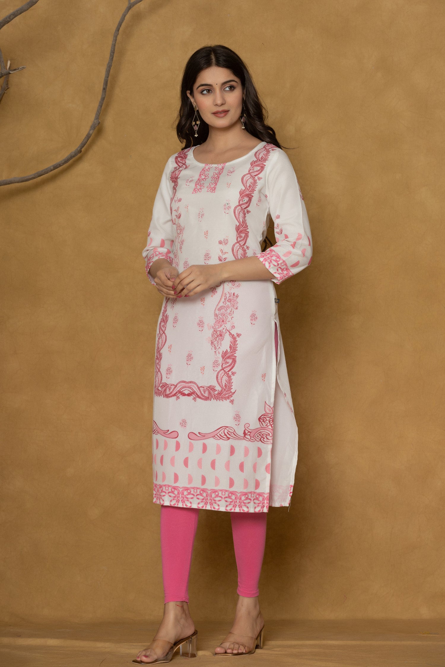 Model wearing a white pannel kurta from The Navra, featuring intricate handwork on the round neck and delicate pink floral patterns along the hemline, paired with bright pink leggings. Ideal for casual and daily ethnic wear.