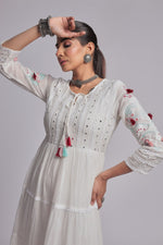 Model in a confident stance, highlighting the full length and comfortable design of the white tiered Anarkali dress with colorful tassels.