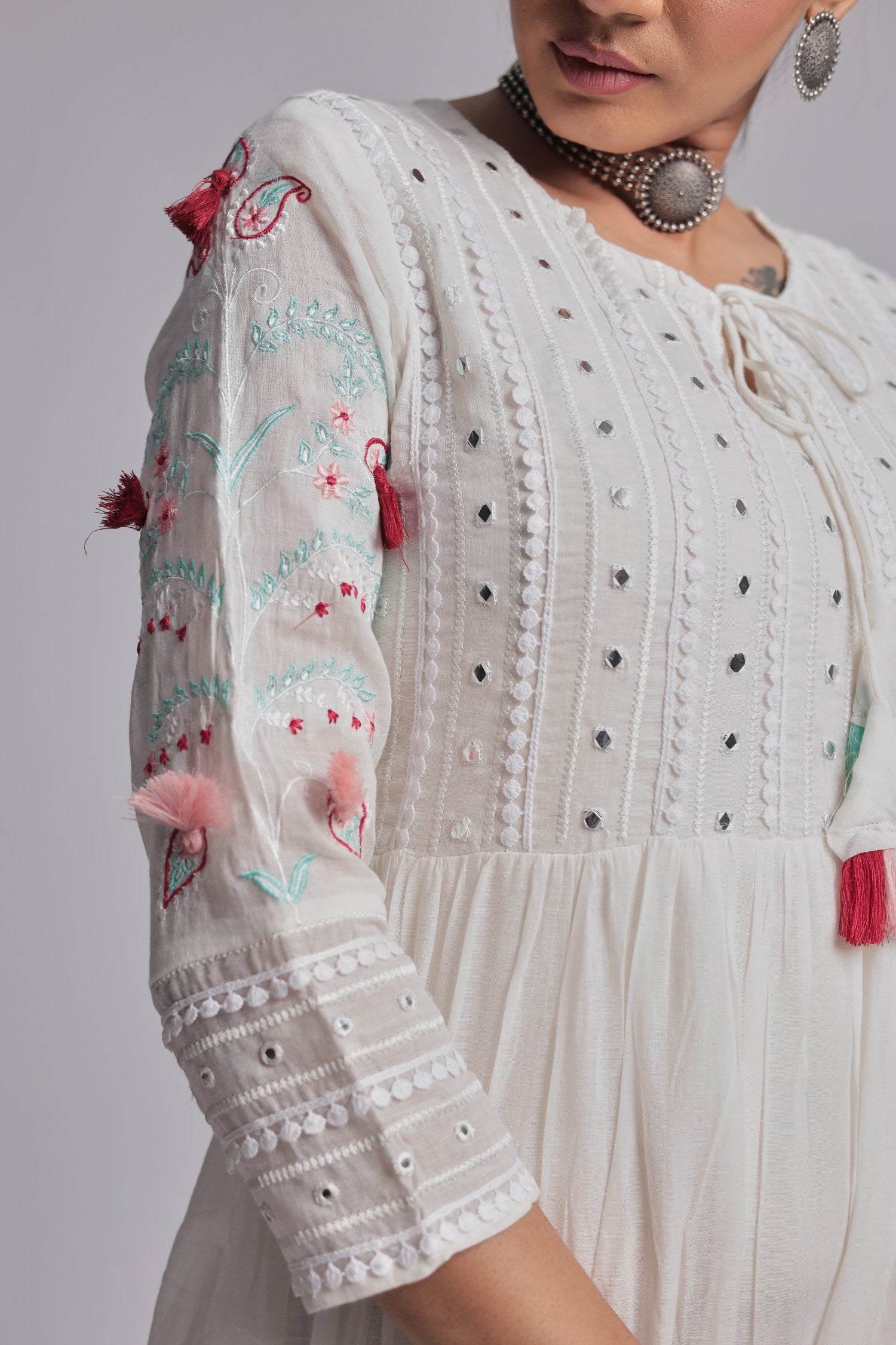 Detailed view of the sleeve and textured fabric of the white tiered Anarkali dress, showing subtle embroidery and embellishments.