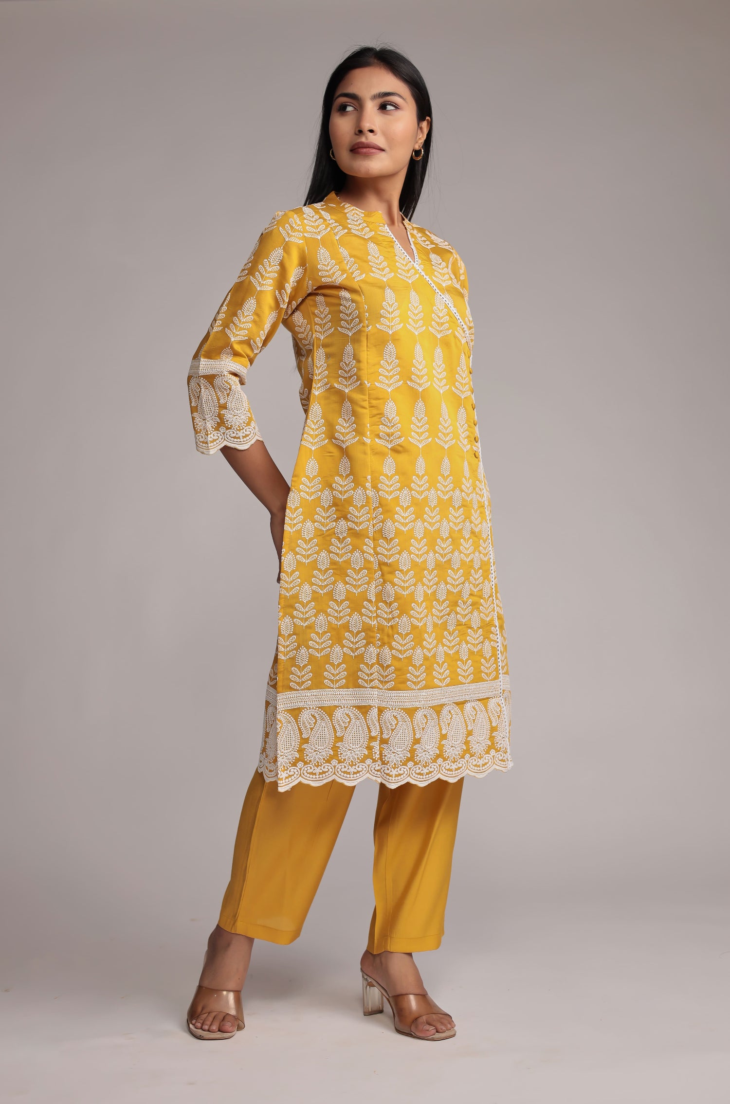 Side profile of model showcasing the comfortable fit and detailed allover embroidery of the yellow kurta pant set.